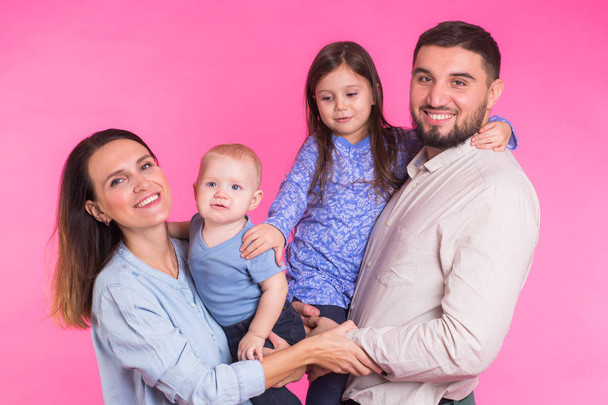 Skvělá rodinná pózuje a usmívá se na kameru společně na růžovém pozadí - Fotografie, Obrázek