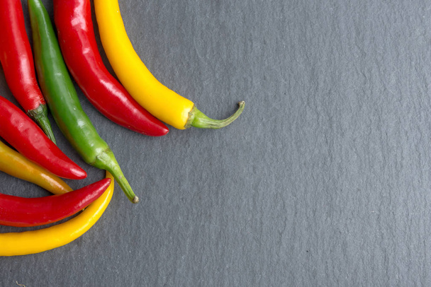 Vibrant peppers on dark slate, flat lay, top view - Valokuva, kuva
