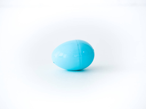 Zbliżenie zdjęcie pojedyncze światła niebieskie plastikowe Pisanka który pochodzi od siebie zabawki, słodycze lub pieniędzy podczas jajko poluje na białym tle na białym tle z otwartej przestrzeni wokół niego. - Zdjęcie, obraz