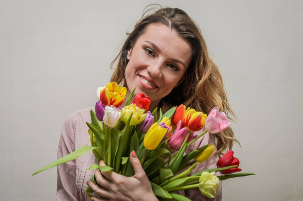 Young charming girl with a bouquet of flowers - multi-colored tulips - Fotografie, Obrázek