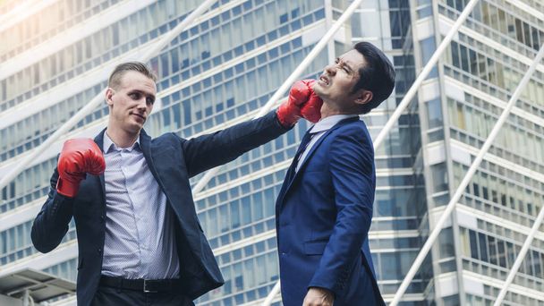 two business mans are fighting with boxing glove at outdoor city - Photo, Image