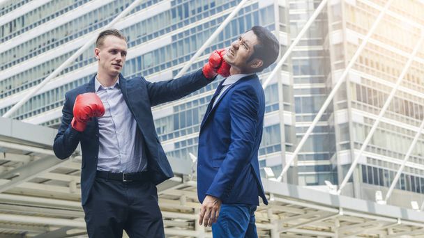 Два бизнесмена дерутся с боксерской перчаткой на открытом воздухе города
 - Фото, изображение