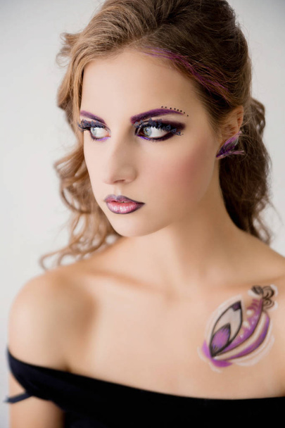 beautiful model with fashion make-up and a picture on the body posing in front of the camera - Foto, imagen