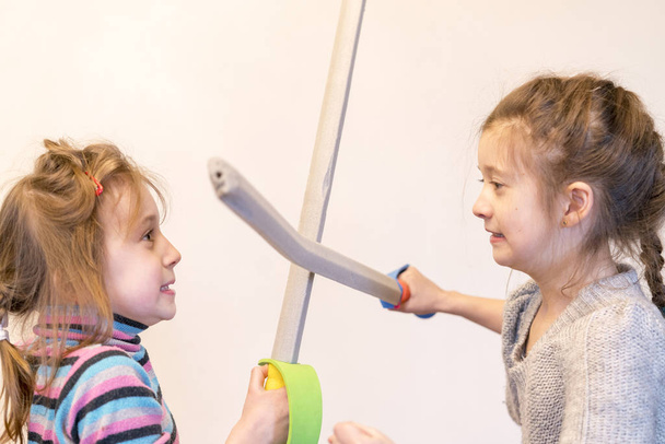 おもちゃの剣で二人の女の子は、騎士を再生します。Deyochki は主張して怒る。競合 - 写真・画像