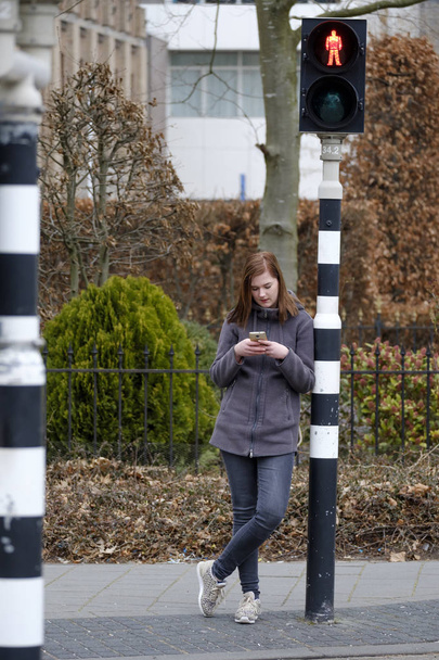 giovane donna guarda il suo cellulare e non presta attenzione a
 - Foto, immagini