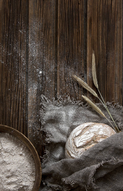 close-up of delicious homemade traditional bread with flour and wheat on wooden background - Fotó, kép