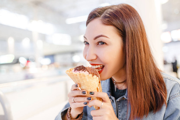 woman eating tasty cone ice-cream in the mall cafe after some shopping - Foto, imagen