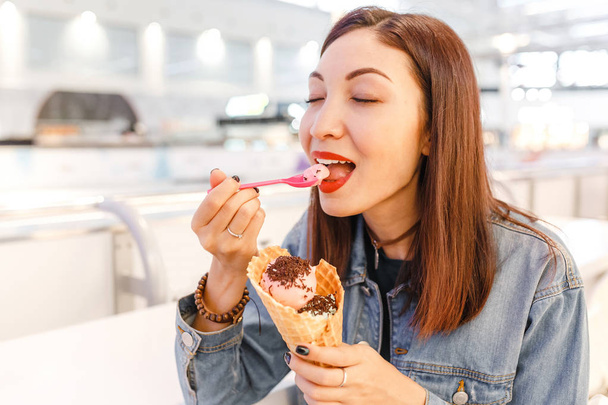mujer comiendo sabroso helado de cono en el café del centro comercial después de algunas compras
 - Foto, Imagen
