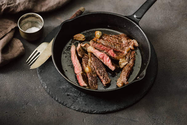 Slices juicy beef steak on vintage cast-iron frying pan - Фото, зображення
