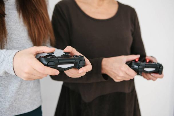Une jeune fille et une femme âgée jouent ensemble dans un jeu vidéo. Un passe-temps commun. La vie familiale. Communication de la grand-mère avec sa petite-fille
. - Photo, image