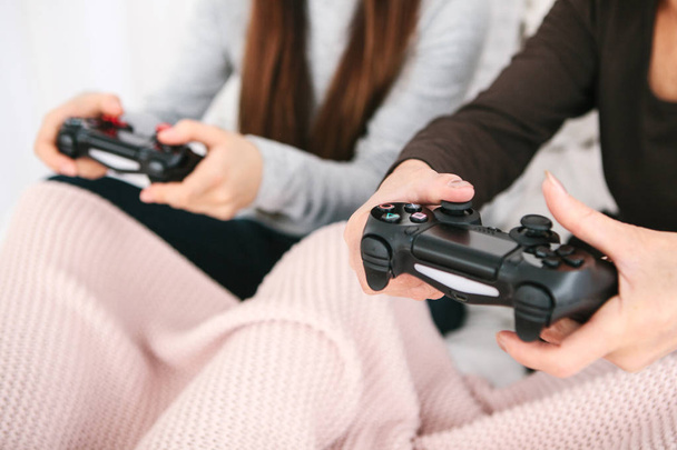 Een jong meisje en een oudere vrouw spelen samen in een video game. Gezamenlijke tijdverdrijf. Gezinsleven. Mededeling van de grootmoeder met haar kleindochter. - Foto, afbeelding