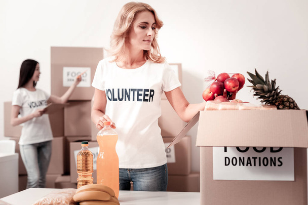 Delighted female person packing charity box - Photo, image