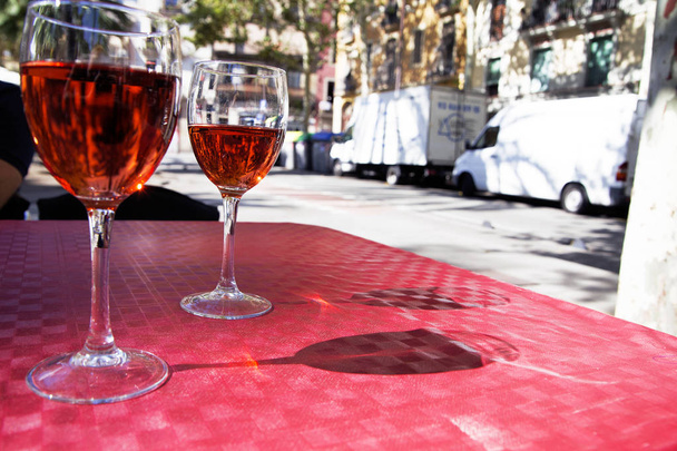két pohár vörös bor az asztalon egy utcai kávézó egy ragyogó napsütéses napon - Fotó, kép
