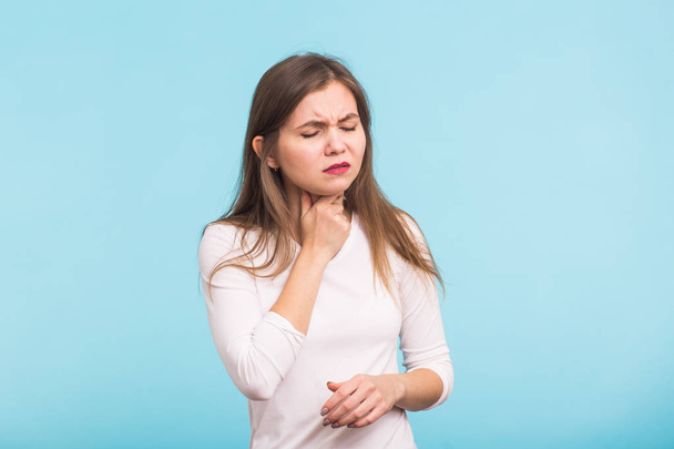 Sore throat. Woman touching the neck on blue background - Foto, Imagen