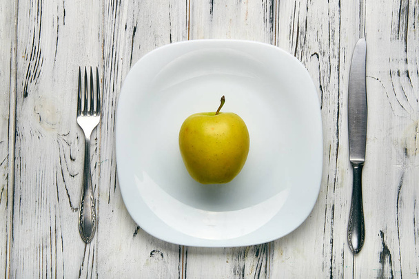 女の子のため厳格な食事療法で女性を食べる。白い平板上大きなジューシー グリーン ファーム アップル。重量を失うために食べ物が少ない。邪悪な栄養士による抗肥満ダイエット. - 写真・画像