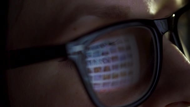 Woman in glasses looking on the monitor and surfing Internet. The monitor screen is reflected in the glasses - Footage, Video
