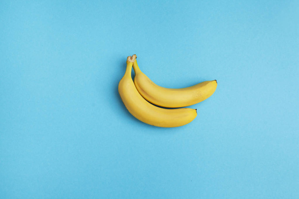 two ripe bananas on blue background - Foto, afbeelding