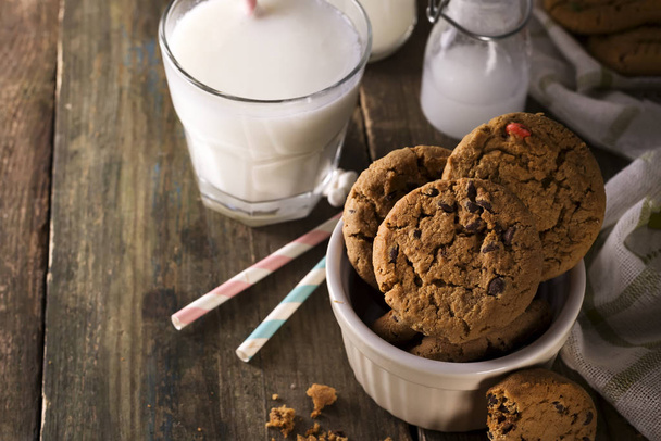 Chocolate chip cookies and milk on a rustic wood background, - Foto, Imagem