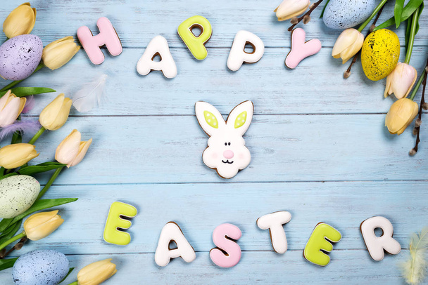 Happy Easter colorful lettering Happy Easter of ginger biscuits and cookies bunny on wooden blue background. - Photo, Image