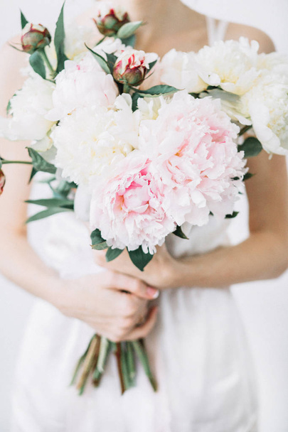 Fiatal nő, rózsaszín és fehér bazsarózsa virágok csokor. Elölnézet. - Fotó, kép