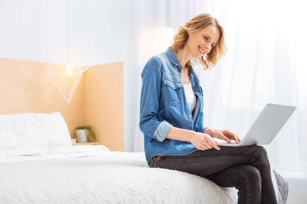 Happy young woman smiling while admiring her new modern laptop - Foto, Bild