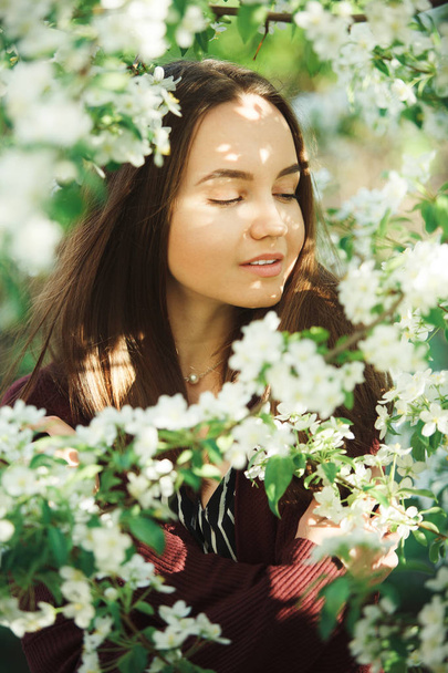 young woman with clean skin near a blooming apple tree. gentle portrait of girl in spring park. - Foto, afbeelding
