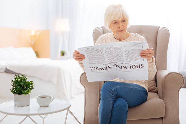 Smart aged person sitting at home and reading the newspaper - Foto, immagini