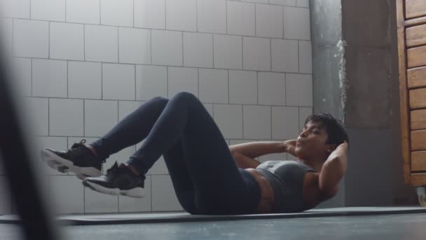 Side View Dolly Video von schwarzer Frau macht einen Bauch Routine auf dem Boden i synny Loft - Filmmaterial, Video