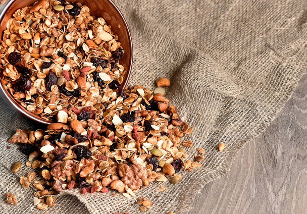 Homemade granola spilling from bowl on wooden table - Photo, image