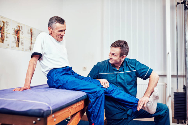 Physiotherapist treating a patient in a patient's office - Foto, imagen