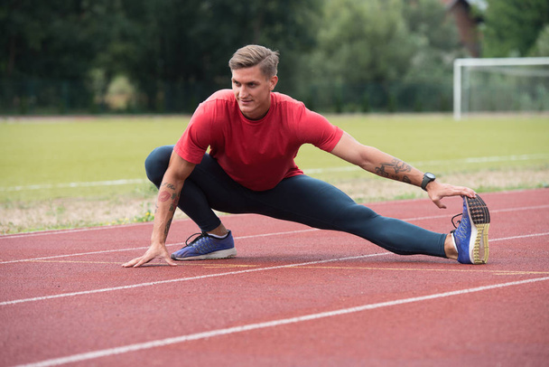 Young Athletic Man Stretching Before Running Exercise - Foto, afbeelding