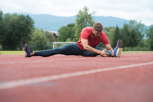 Fitness Man Stretching Before Workout Running on Track - Foto, afbeelding