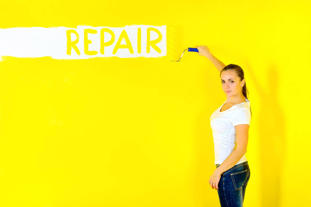 girl painter paints the wall with a roller, paints the repair on the wall - Photo, image