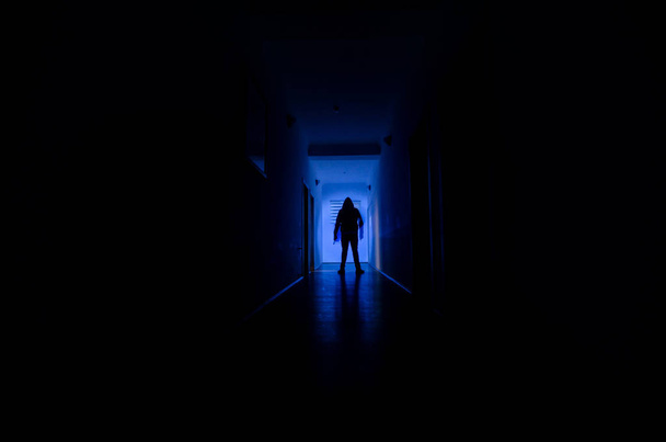 キャビネットの扉や不気味なホラーに異なるポーズで立っている男のシルエットが付いているライトで暗い廊下. - 写真・画像