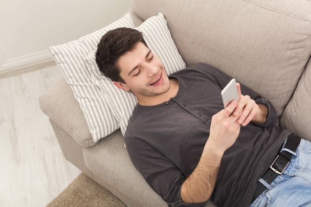 Young man messaging on smartphone at home - Φωτογραφία, εικόνα