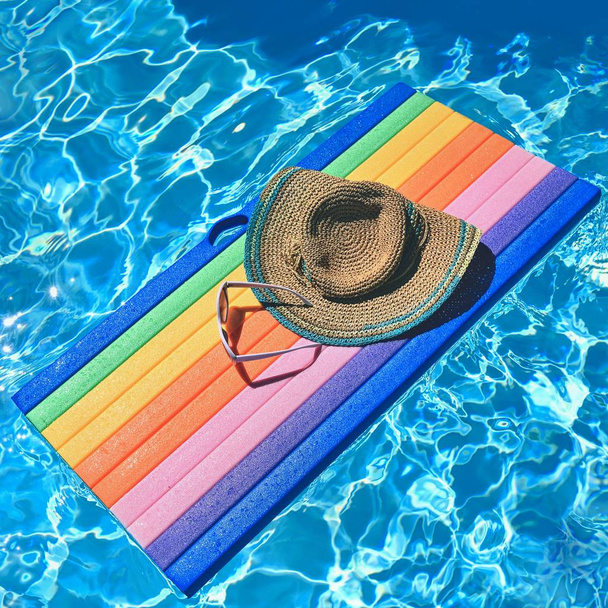 Gafas de sol, lilo y sombrero en el agua en un día soleado caliente. Fondo de verano para viajar y vacaciones. Vacaciones idílicas
. - Foto, Imagen