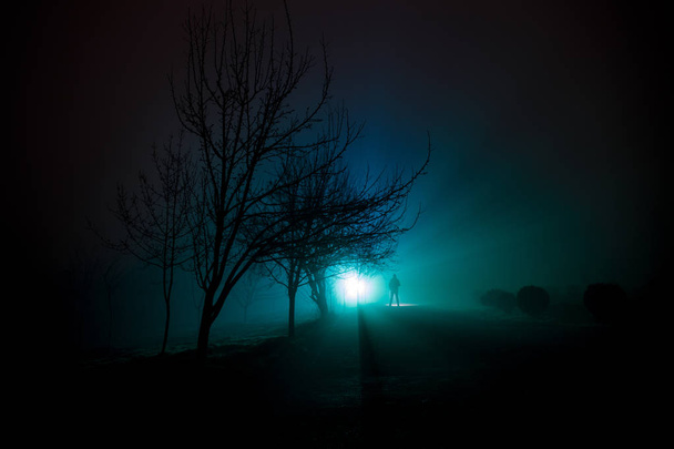 Miasta w nocy w gęstej mgle. Mistyczny krajobraz surrealistyczne światła z creepy człowieka. Sylwetka człowieka spaceru w mgły w nocy przy sztucznym świetle. Piękna, mieszane oświetlenie z tyłu. - Zdjęcie, obraz