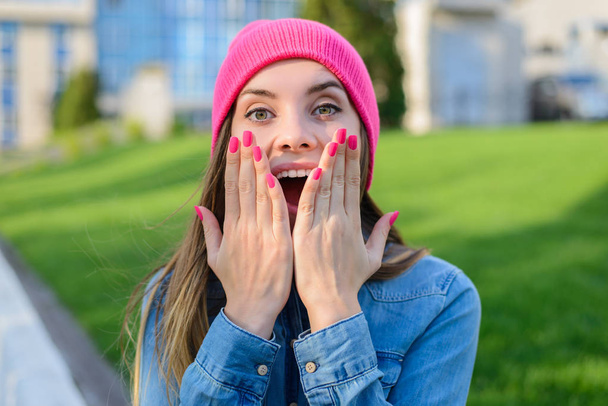 Ευτυχισμένη χαρούμενη έκπληξη εφηβικό κορίτσι στο ροζ καπέλο, με ροζ νύχι - Φωτογραφία, εικόνα