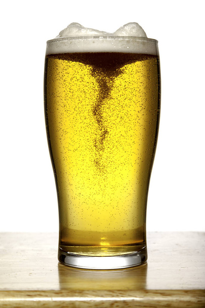 Ποτήρι μπύρας με αφρό σε ξύλο και λευκό - Φωτογραφία, εικόνα