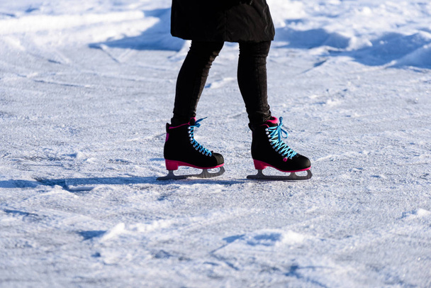 young woman in black coat skating on the frozen lake in snow, le - Foto, Imagen
