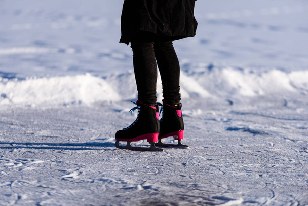 黒のコートが雪で凍った湖の上でスケートの若い女性ル - 写真・画像