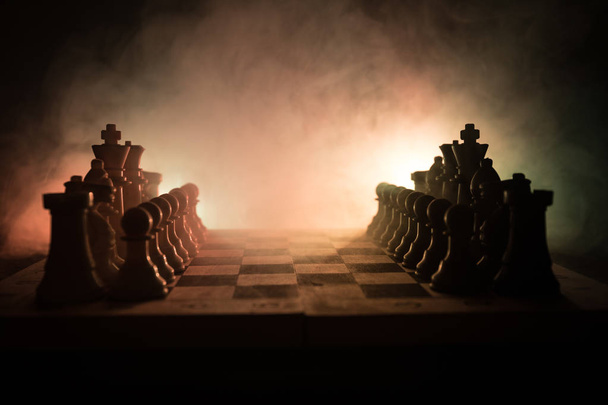 Schaken bordspel concept van bedrijfsideeën en concurrentie en strategie ideeën concep. Chess cijfers op een donkere achtergrond met rook en mist. Leiderschap en vertrouwen bedrijfsconcept. - Foto, afbeelding