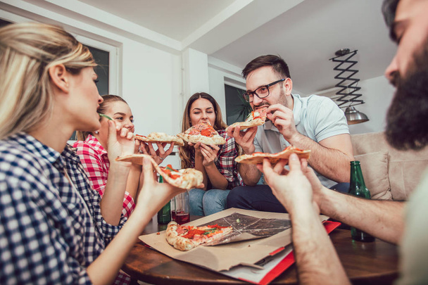 ピザを食べる若い友人のグループ。ホームパーティー。. - 写真・画像