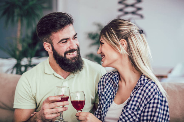 schönes romantisches Paar, das romantische Momente hat, Rotwein trinkt, während es den Valentinstag oder das Jubiläum zu Hause feiert - Foto, Bild
