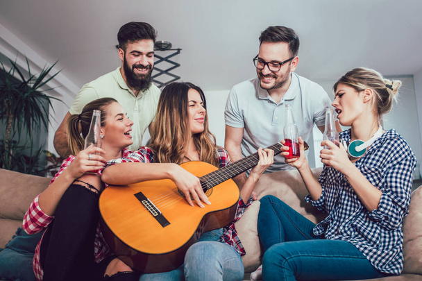 Groep van gelukkige jonge vrienden die plezier hebben en bier drinken in het interieur - Foto, afbeelding