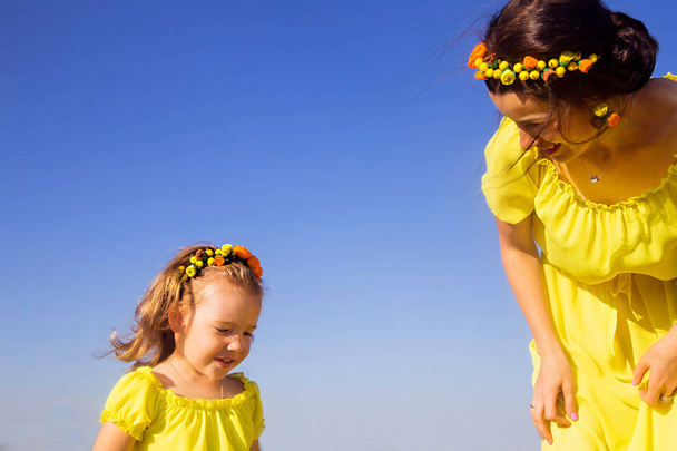 Mom and daughter in identical yellow dresses have fun - Photo, Image