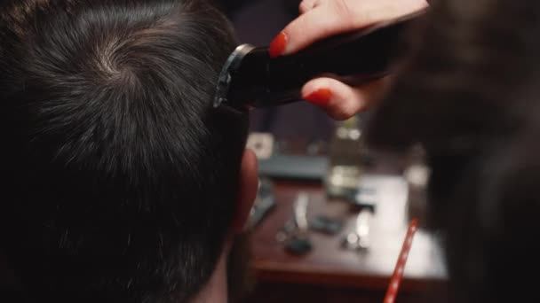 Barber cuts the hair of the client with trimmer close-up - Materiaali, video