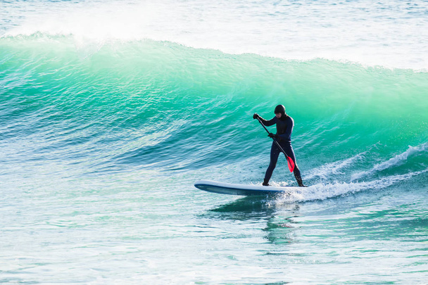 Surfař na stand up paddle board na modré vlně. Zima surfování v oceánu - Fotografie, Obrázek