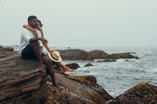 Young couple on the stone neat ocean - Foto, Imagen