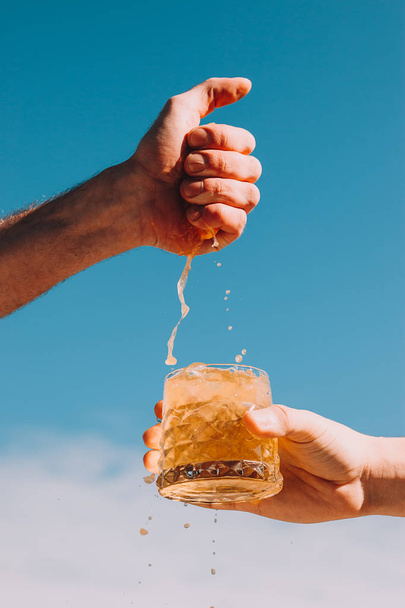 Exprimir el jugo de naranja por las manos en limonada con hielo
 - Foto, imagen